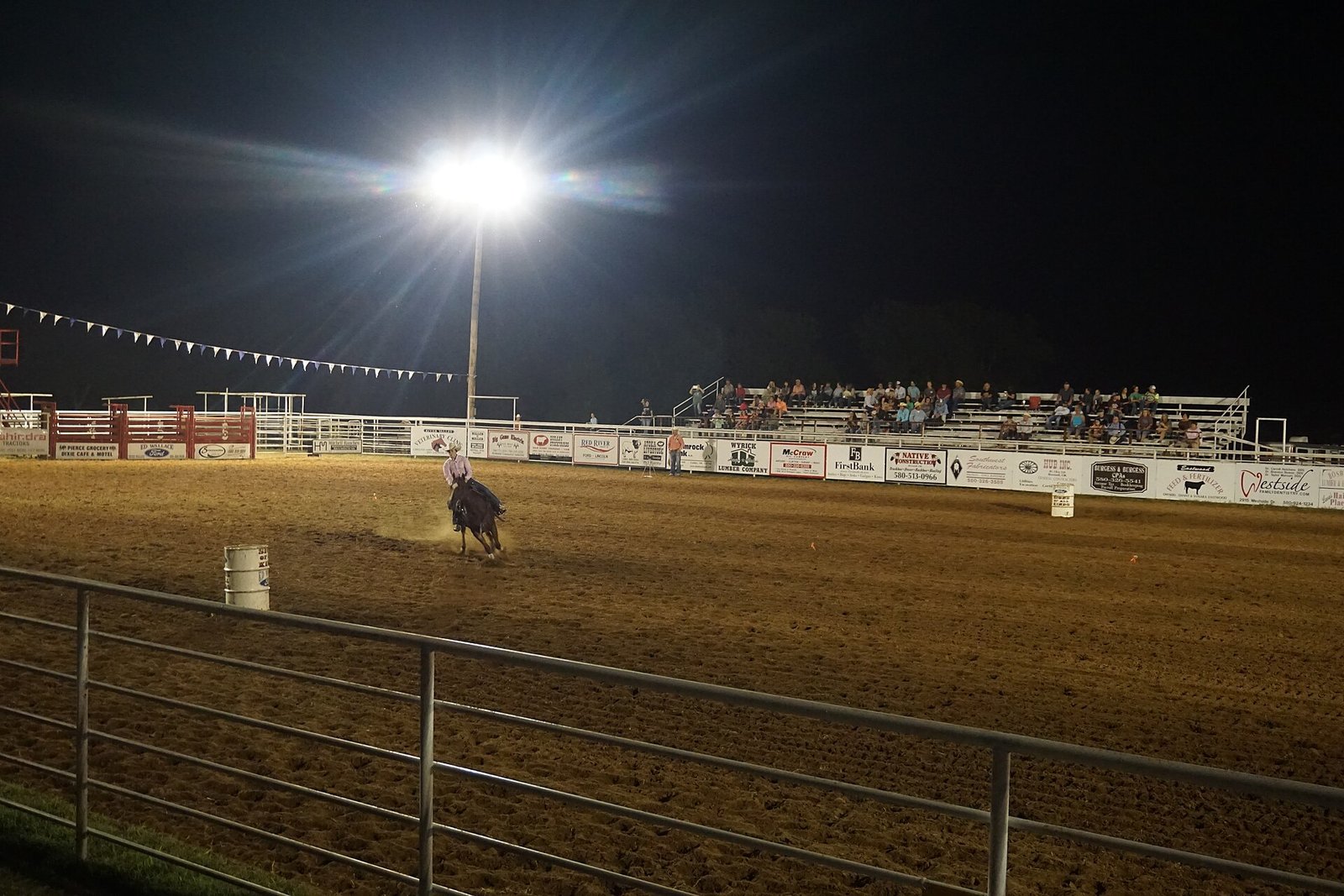 Barrel racer rounding a barrel at an indoor rodeo arena